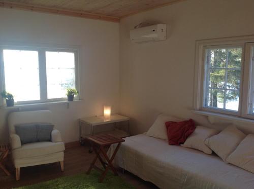 a bedroom with a bed and a chair and windows at Houses by the sea near the city in Lidingö