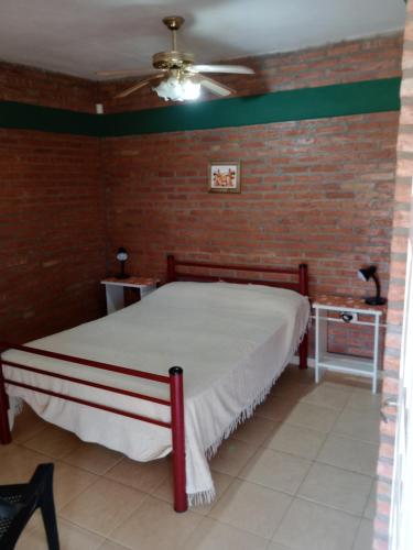 a bedroom with a bed and a brick wall at Los nidos 3 in Villa Cura Brochero