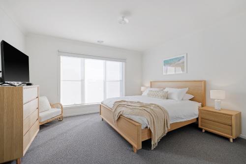 Schlafzimmer mit einem Bett, einem TV und einem Fenster in der Unterkunft Shore to Please - BYO LINEN & TOWELS in Cowes