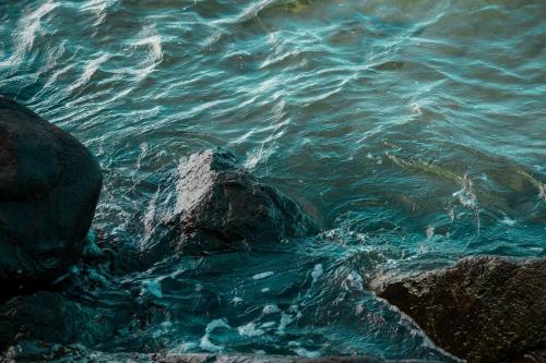 a body of water with rocks in the water at Kasakai Beachouse in Juan Gallego
