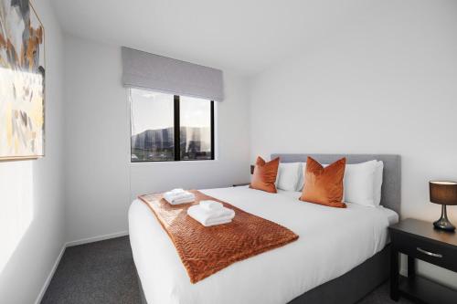 um quarto com uma grande cama branca com almofadas laranja em Remarkable Mountain Scene - A Modern Escape em Frankton