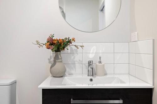um lavatório de casa de banho com um vaso com flores em Remarkable Mountain Scene - A Modern Escape em Frankton