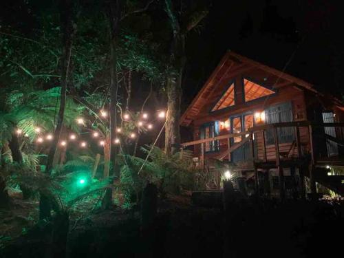 una cabaña con luces en el bosque por la noche en Refúgio Amor Demasiado, en São Francisco de Paula