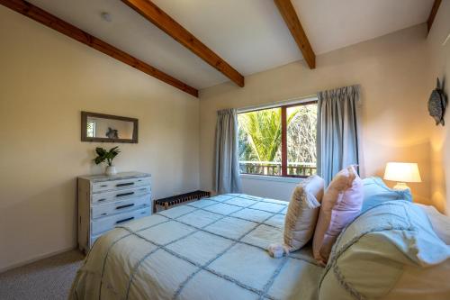 a bedroom with a large bed and a window at Onetangi Beach Retreat - Waiheke Holiday Home in Onetangi