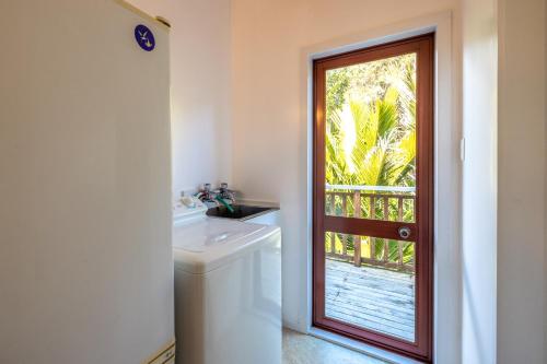 a bathroom with a sink and a door with a window at Onetangi Beach Retreat - Waiheke Holiday Home in Onetangi