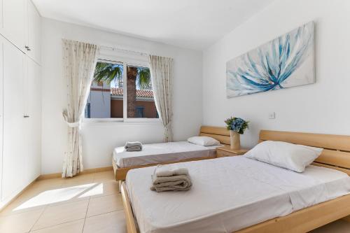1 dormitorio con 2 camas y ventana en Antonia's Palace Rooftop Jacuzzi Stunning View en Pafos
