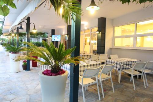 restauracja ze stołami, krzesłami i roślinami w obiekcie Hotel Alexandros w mieście Nei Pori
