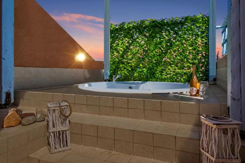 een bad in een badkamer met een groot raam bij Antonia's Palace Rooftop Jacuzzi Stunning View in Paphos City