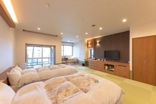 een grote kamer met een rij witte bedden bij Chikuba Shinyotei in Hakodate