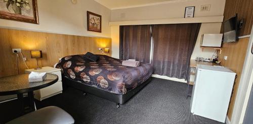 a hotel room with a bed and a table at Blue Lake Motel in Mount Gambier