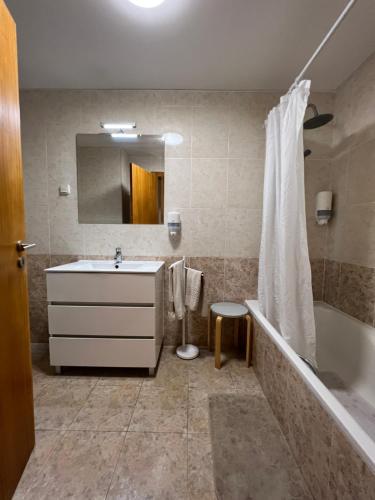 a bathroom with a sink and a tub and a mirror at Apartamento do Atlântico in Ponta Delgada