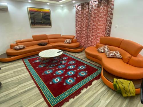 a living room with two couches and a rug at Résidence El Hadji Annexe in Dakar