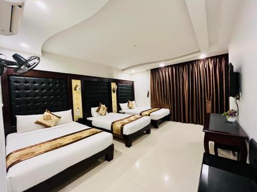 a hotel room with three beds and a desk at Hồng Anh 2 Hotel in Ha Long