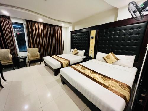 a hotel room with two beds and a chair at Hồng Anh 2 Hotel in Ha Long