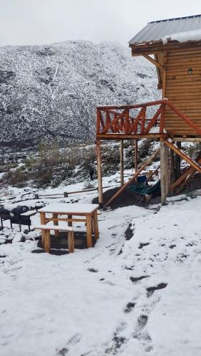 a picnic table and bench in the snow next to a cabin at Cabaña Rincón del Sol in Potrerillos