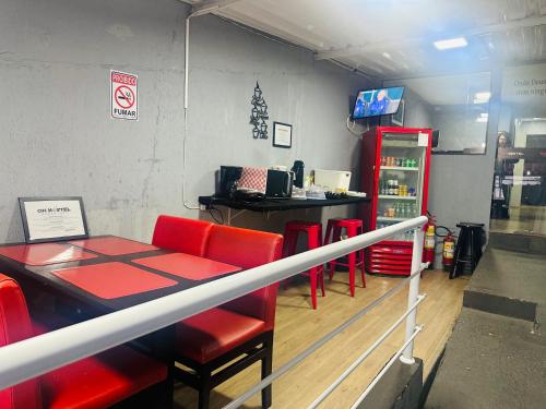 un restaurante con mesa, sillas rojas y barra en ON HOSTEL II Gru Aeroporto Translado 24 hs, en Guarulhos