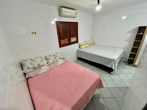 Cette petite chambre comprend 2 lits et une fenêtre. dans l'établissement Casa Ilha de Itamaracá, à Vila Velha