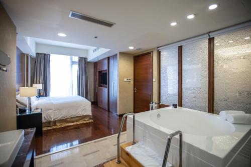 a bathroom with a bath tub and a bed at The Imperial Mansion, Beijing - Marriott Executive Apartments in Beijing