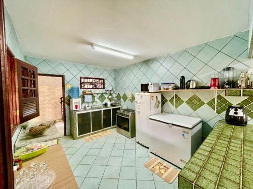 a kitchen with a white refrigerator and green tiles at Casa Ilha de Itamaracá in Vila Velha
