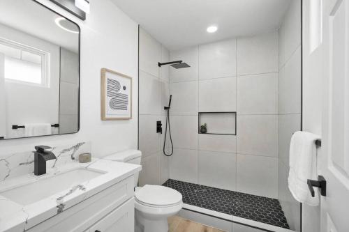 a white bathroom with a shower and a toilet at Serenity by the Sea Ultimate Beachfront Escape in Hauula