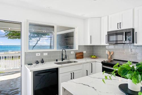 a kitchen with white cabinets and a view of the ocean at Serenity by the Sea Ultimate Beachfront Escape in Hauula
