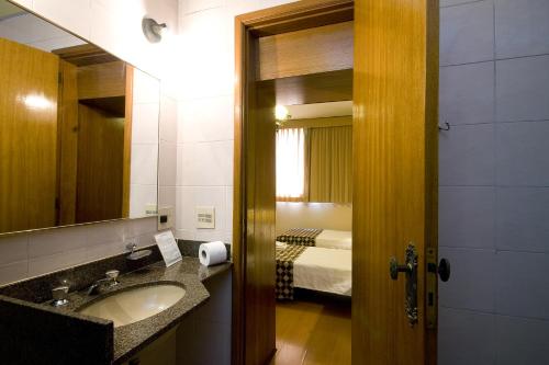 uma casa de banho com um lavatório, um espelho e uma cama em Hotel Rondônia Palace no Rio de Janeiro