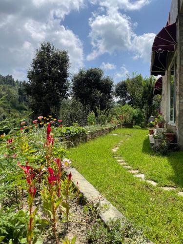 a garden with flowers on the side of a house at Francolin Lodge-Farmstay @ Darima in Mukteswar