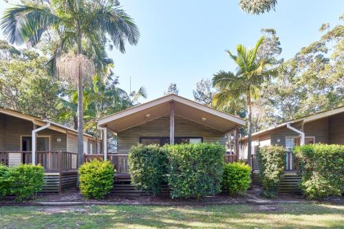 a house with trees and bushes in front of it at NRMA Ocean Beach Holiday Resort in Umina