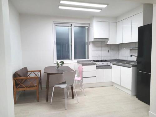 - une cuisine avec des placards blancs, une table et des chaises dans l'établissement Elle House 2, à Jeonju