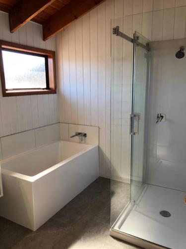 La salle de bains est pourvue d'une baignoire et d'une douche en verre. dans l'établissement Alpine Motel, à Ohakune