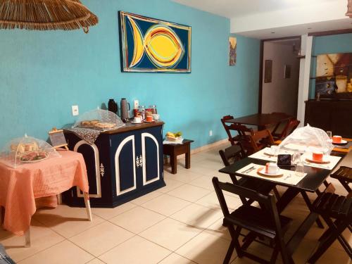 una habitación con mesas y sillas y una pared azul en La Tana del Tano Guest House, en Búzios