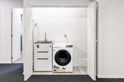 a washer and dryer in a white bathroom at Okiwi Landing in Raglan