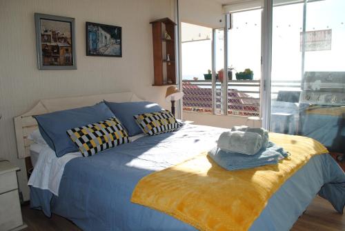 1 dormitorio con 1 cama con almohadas azules y amarillas en Departamento de Vynka en Algarrobo