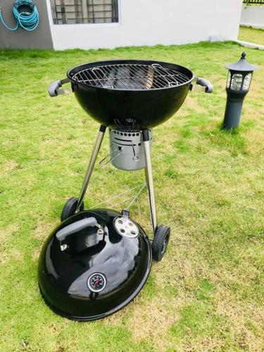a barbecue grill sitting on the grass in a yard at Binbaba Homestay - Grand Maganda in Batam Center