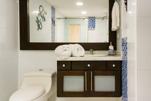 Un baño con inodoro, lavabo y espejo. en Casa Pepper Hill, en San Andrés