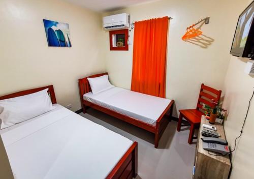 Zimmer mit 2 Betten, einem Stuhl und einem TV in der Unterkunft Downtown Suites CDO in Cagayan de Oro