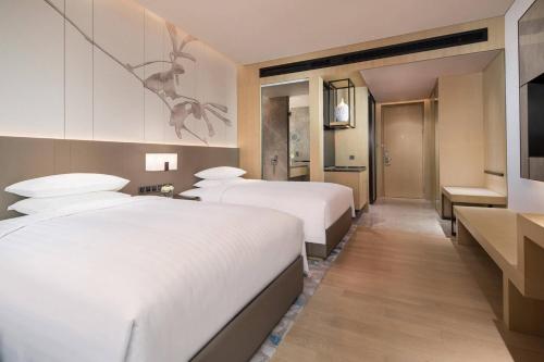 QingpuにあるCourtyard by Marriott Shanghai Hongqiaoのベッド3台とキッチンが備わるホテルルームです。