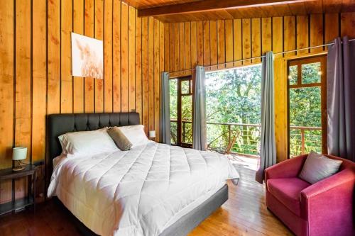 1 dormitorio con 1 cama, 1 silla y 1 ventana en Wildlife Refuge’s Wood Cabin en Monteverde