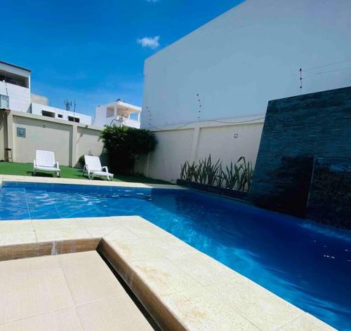 a swimming pool with two chairs and a house at Deluxeguesthouse/vía Spondylus in Manta
