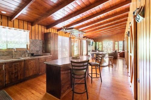 una cocina con suelo de madera y un bar con taburetes en Wildlife Refuge’s Wood Cabin, en Monteverde