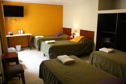 a room with three beds and a table and a desk at Hotel Acuario in Churín