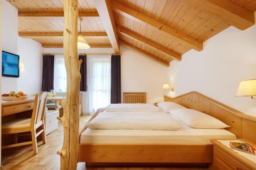 a bedroom with a large bed with a desk and a bed sidx sidx sidx sidx at Alpin Stile Hotel in Laion