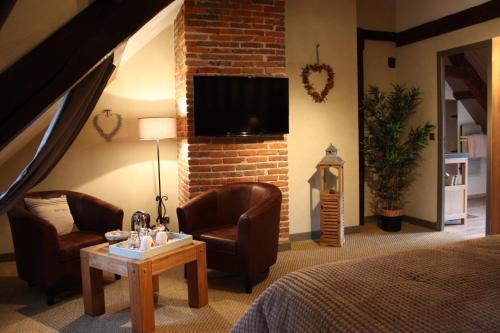 a bedroom with a bed and two chairs and a tv at Les Songes d'Héléna in Honfleur