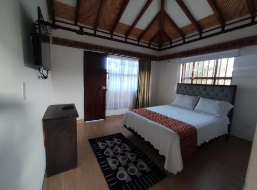 um quarto com uma cama grande e piso em madeira em Hotel Artemisa em Sutamarchán