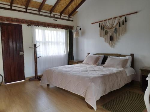 um quarto com uma cama e uma cruz na parede em Hotel Artemisa em Sutamarchán