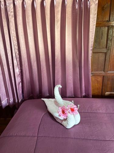 a purple bed with an elephant shaped towel with flowers on it at The Best Garden resort in Sichon