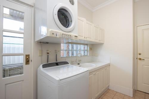 a white laundry room with a washing machine and a sink at Durham Lodge Bed & Breakfast in Perth