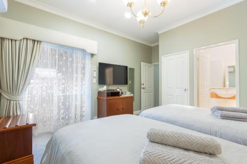 a bedroom with two beds and a tv at Durham Lodge Bed & Breakfast in Perth