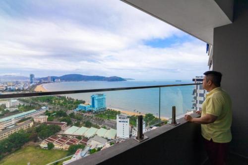 Un uomo in piedi su un balcone che guarda l'oceano di FLC Sea Tower Quy Nhơn - Homostay a Quy Nhon