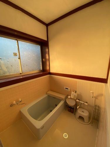 a bathroom with a bath tub and a toilet at Wakamizu Minpaku in Tōganemachi